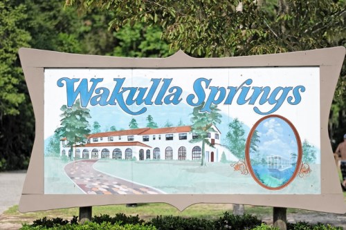 Sign for Wakulla Springs featuring a scenic illustration and text in a decorative font.