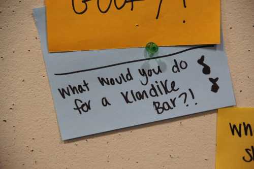 A blue sticky note on a wall asks, "What would you do for a Klondike Bar?!" with playful doodles.