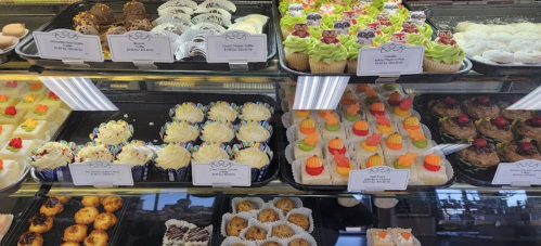 A display case filled with various colorful cupcakes and desserts, including decorated cupcakes and cookies.