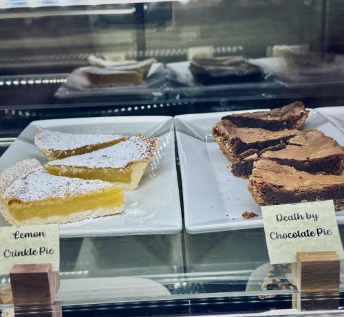 Two dessert plates: one with lemon crinkle pie and the other with death by chocolate pie, both displayed in a glass case.