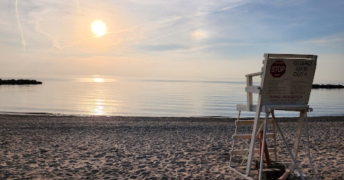A serene beach at sunset with calm waters and a lifeguard chair in the foreground.