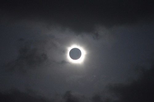 A solar eclipse with the moon partially covering the sun, surrounded by dark clouds.