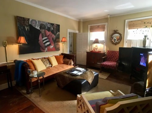 Cozy living room with a mix of vintage furniture, a large painting, and warm lighting.