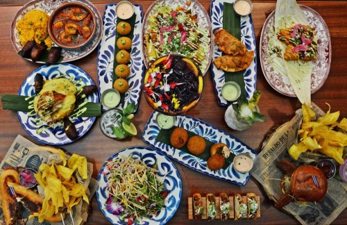 A vibrant spread of various dishes, including appetizers, salads, and desserts, arranged on colorful plates.