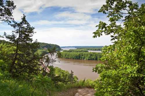 A scenic view of a river winding through lush greenery under a partly cloudy sky.