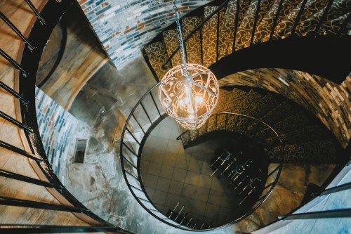 Aerial view of a spiral staircase with a decorative light fixture and patterned steps.
