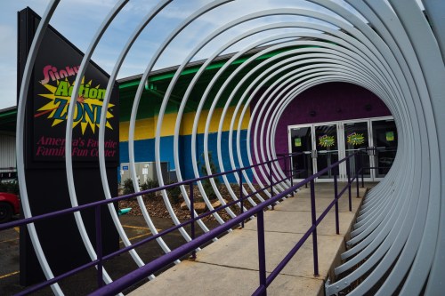 Entrance to a colorful family fun center with a spiral tunnel leading to the doors.