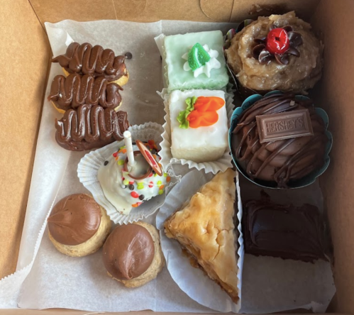 A box of assorted desserts including cupcakes, pastries, and chocolate treats, beautifully arranged.