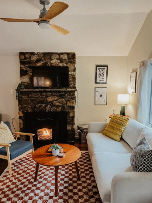Cozy living room with a stone fireplace, a white sofa, wooden coffee table, and decorative wall art.