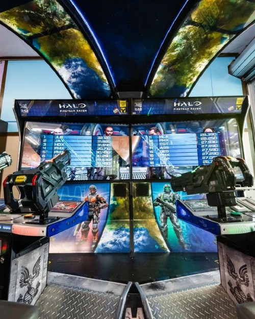 Arcade setup featuring two Halo-themed gaming stations with vibrant graphics and a space-themed backdrop.