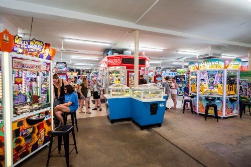 A vibrant arcade filled with various games and machines, with people enjoying their time in a lively atmosphere.