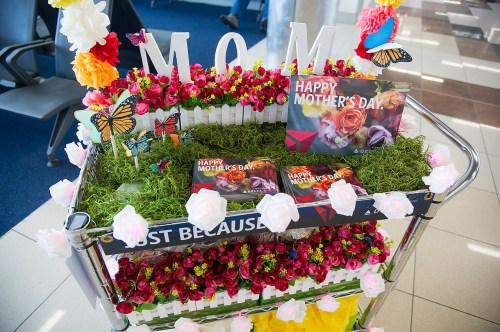 A decorated cart with flowers, butterflies, and a "Happy Mother's Day" sign, celebrating Mother's Day.