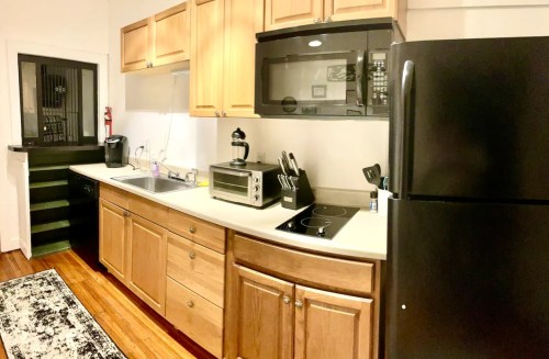Modern kitchen with wooden cabinets, stainless steel appliances, and a black refrigerator, featuring a sink and countertop.