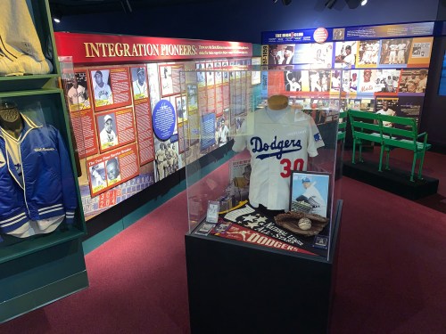 Exhibit showcasing baseball memorabilia, including a Dodgers jersey, photos, and information on integration pioneers.