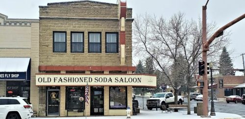 Historic building with "Old Fashioned Soda Saloon" sign, snowy street, and traffic light in a small town setting.