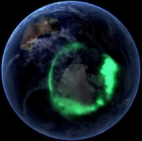 A view of Earth from space showing a green aurora over Antarctica, highlighting the planet's atmospheric phenomena.