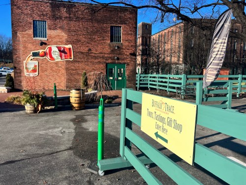 A brick building with a large bottle mural, featuring a gift shop sign and outdoor seating area.