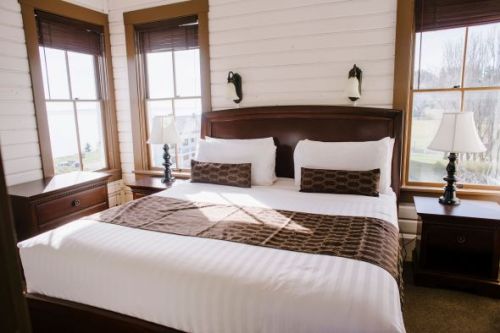 Cozy bedroom with a large bed, two lamps, and windows letting in natural light. Warm, inviting decor.