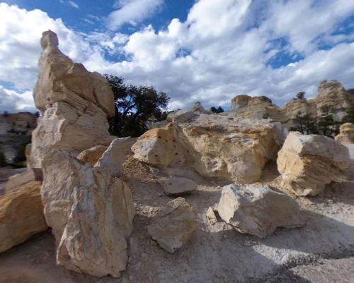 Rock formations under a partly cloudy sky, showcasing various shapes and textures in a natural landscape.