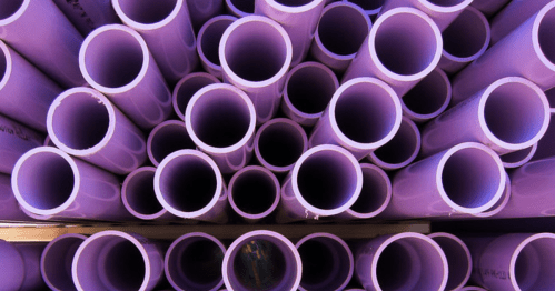 A close-up view of numerous purple PVC pipes stacked together, showcasing their circular openings.