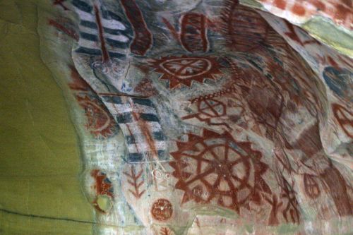 Ancient cave paintings featuring geometric patterns and symbols in earthy tones on a rock surface.