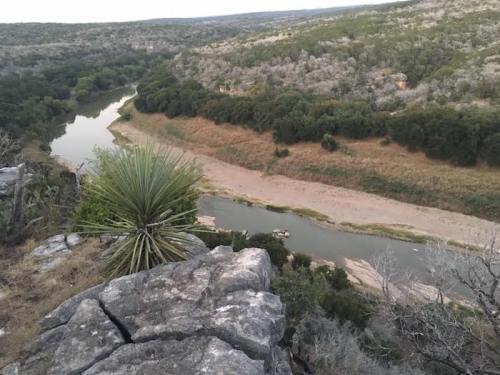 A scenic view of a winding river surrounded by rocky terrain and lush greenery.