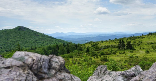 A scenic view of rolling green hills and distant mountains under a partly cloudy sky.