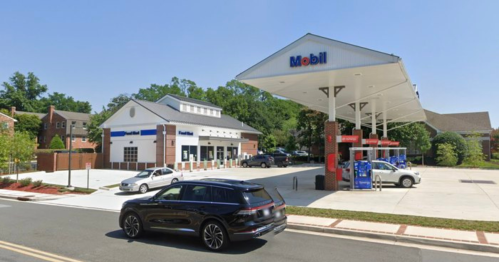 A Mobil gas station with a convenience store, featuring several cars parked and a clear blue sky.