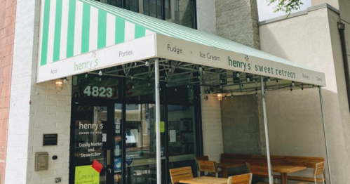 Exterior of "Henry's Sweet Retreat" with a striped awning, featuring signs for fudge, ice cream, and candy market.