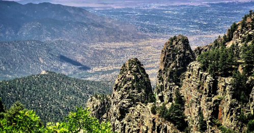 A scenic view of rugged mountains and valleys, with peaks rising above a vast landscape in the distance.