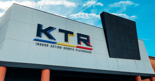 Exterior of KTR Indoor Action Sports Playground, featuring a colorful sign against a blue sky.