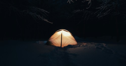 Winter camping tent glowing in snow at Cross Ranch State Park, North Dakota.
