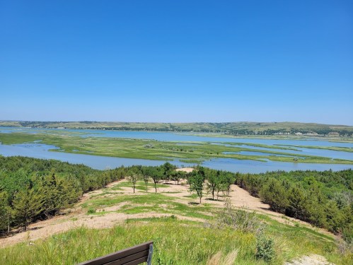 A scenic view of a lush green landscape with a winding river under a clear blue sky.