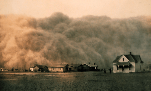 A dust storm looms over a small town, with houses partially obscured by swirling clouds of dust.