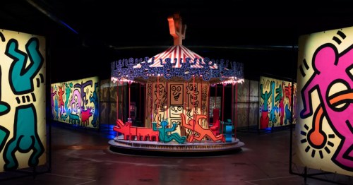 A colorful carousel surrounded by vibrant, illuminated panels featuring playful, abstract figures.