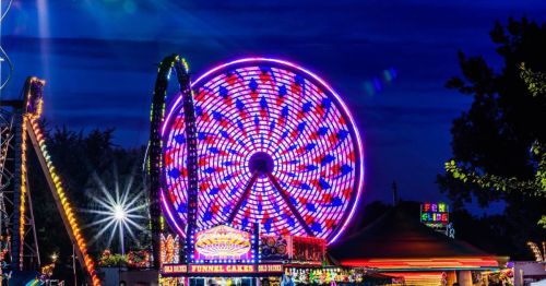 A vibrant ferris wheel illuminated with colorful lights at night, surrounded by carnival attractions.
