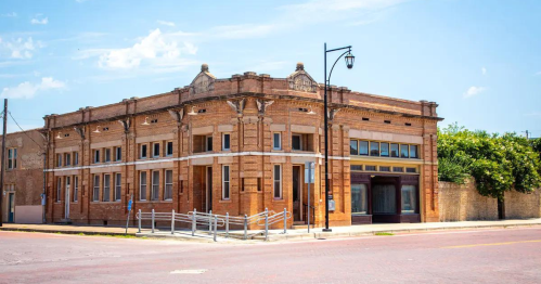 Historic brick building with decorative architecture, located on a street corner under a clear blue sky.