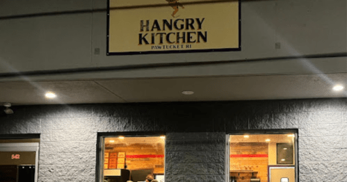 Sign for "Hangry Kitchen" in Pawtucket, RI, with a view of the restaurant's entrance and windows at night.
