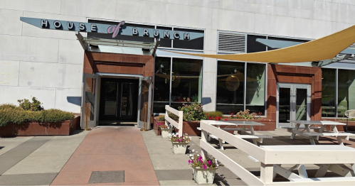 Exterior of "House of Brunch" restaurant with outdoor seating and flower planters under a shaded awning.