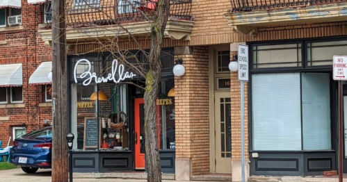 A street view of a café named "Gravelle's" with a cozy entrance, surrounded by brick buildings and parked cars.