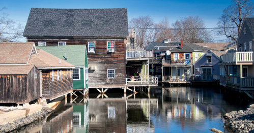 A scenic view of colorful houses on stilts by a calm waterway under a clear blue sky.
