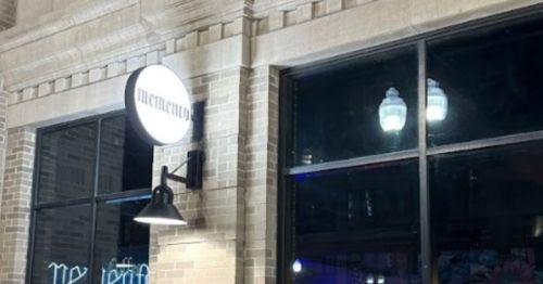 A nighttime view of a building exterior featuring a sign that reads "memento" and illuminated windows.