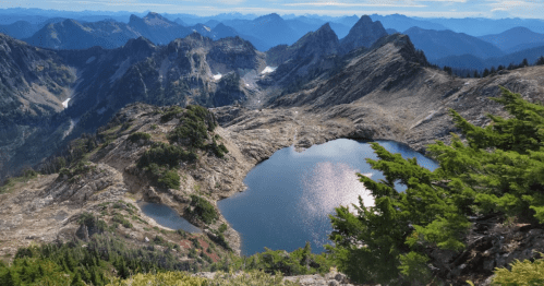 A scenic mountain landscape featuring a serene lake surrounded by rugged peaks and lush greenery.