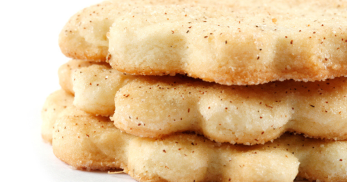 Close-up of three stacked, lightly golden-brown cookies with a textured surface.