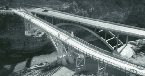 Black and white image of two bridges spanning a river, showcasing different architectural designs.