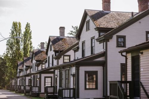 A row of charming, two-story houses with gabled roofs and porches, lined along a quiet street.
