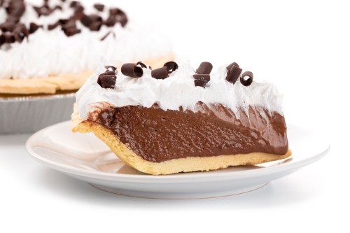A slice of chocolate cream pie topped with whipped cream and chocolate shavings on a white plate.
