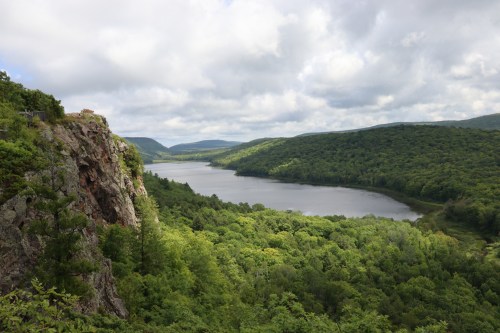 A scenic view of a river winding through lush green hills under a cloudy sky.