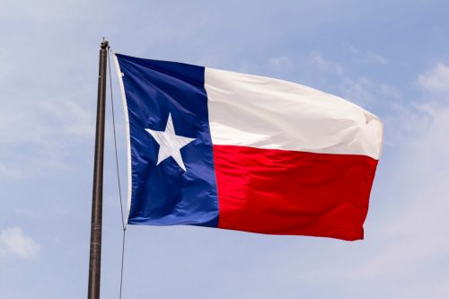 Texas state flag waving against a blue sky.