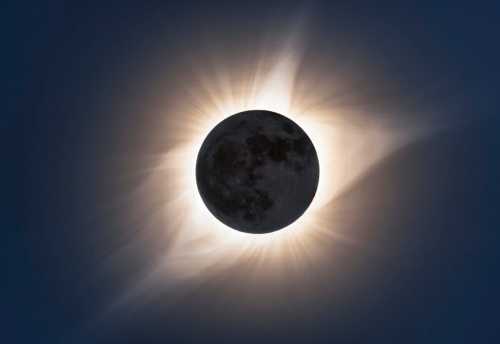 A solar eclipse with the moon partially covering the sun, surrounded by glowing solar corona and dark sky.